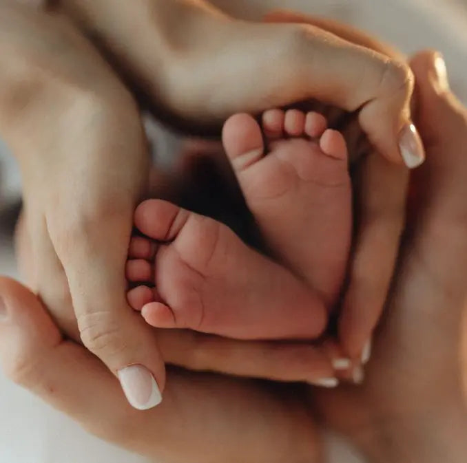 Mãos de mãe a segurar os pézinhos de um recém-nascido